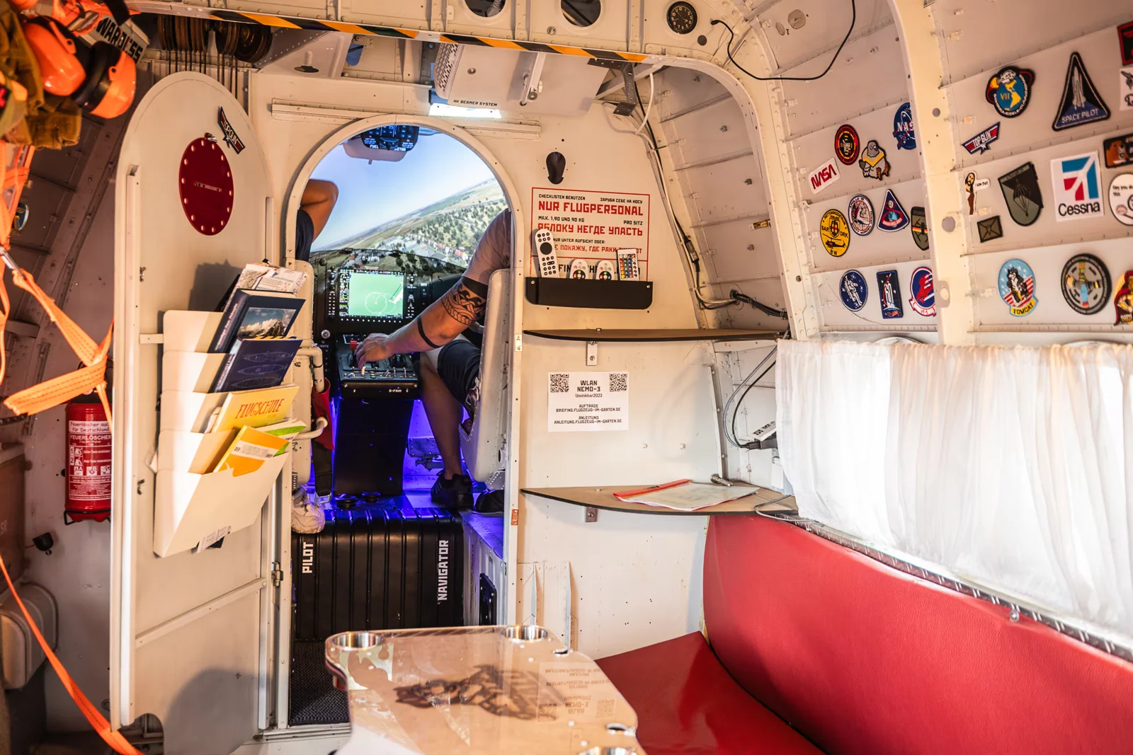 View through the Antonov cabin with red bench seating, a table and open cockpit